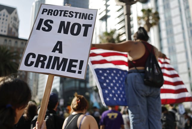 LOS ANGELES, CALIFORNIA - JUNE 11: A person holds a "Protesting Is Not A Crime!" sign as people demonstrate before marching downtown as protests against ICE immigration raids continue in the city on June 11, 2025 in Los Angeles, California. Tensions in the city remain high with daily protests after the Trump administration called in the National Guard and the Marines against the wishes of Gov. Gavin Newsom and city leaders. (Photo by Mario Tama/Getty Images)