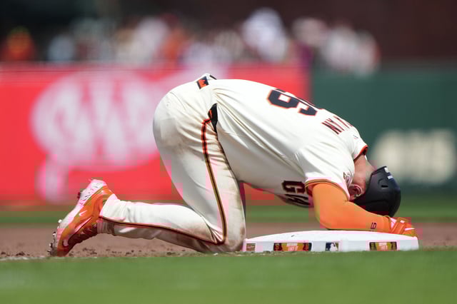 Matt Chapman of the San Francisco Giants on his knees in pain after he was picked off diving back into first base against the Atlanta Braves in the bottom of the eighth inning of a major league baseball game at Oracle Park on June 08, 2025 in San Francisco, California. 