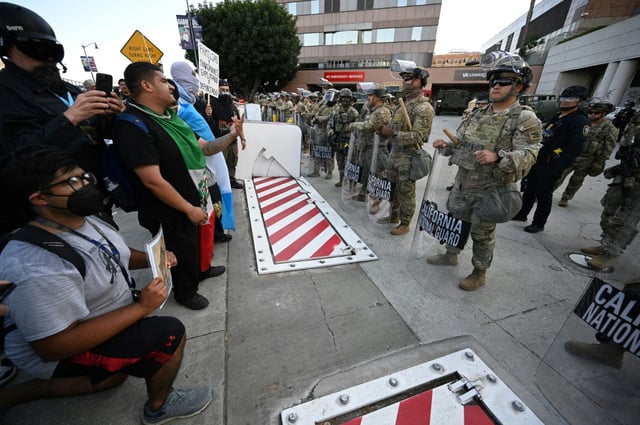Protestors stand in front California National Guard members at a federal building in Los Angeles, just blocks from where theater-goers were to attend a performance of Shakespeare's Hamlet on June 13, 2025