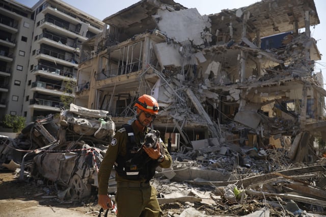 An emergency worker carries a rescued dog named Tes from a building damaged in an overnight strike on June 14, 2025 in Ramat Gan, Israel.