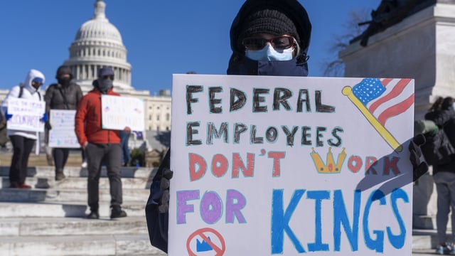 A federal employee, who asked not to use their name for fears over losing their job, protests with a sign saying 'Federal Employees Don't Work for Kings' during the 'No Kings Day' protest on Presidents Day near the Capitol in Washington.