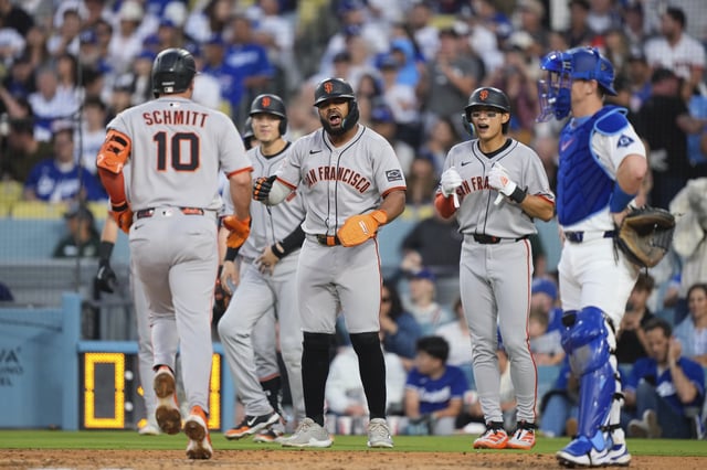 San Francisco Giants' Casey Schmitt, left, is congratulated by teammates after hitting a grand slam as Los Angeles Dodgers catcher Will Smith, right, sands by during the third inning of a baseball game Friday, June 13, 2025, in Los Angeles. (AP Photo/Mark J. Terrill)