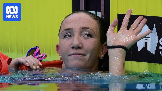 Australian swimmer Lani Pallister in the pool raises her hand to acknowledge the crowd after a race.