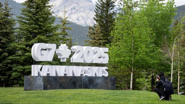 Ein Fotograf vor einem Schild zum G7-Gipfel in Kananaskis