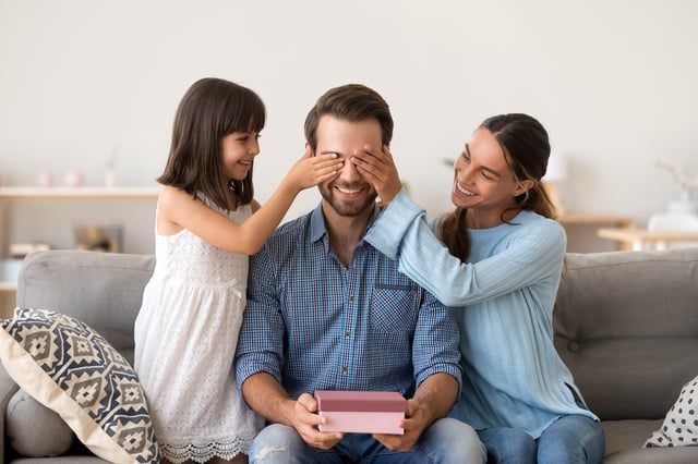 Un moment de tendresse pour la fête des pères : une petite fille et sa mère offrent un cadeau à leur papa. Découvrez l’origine de cette tradition célébrée à différentes dates à travers l’Europe.