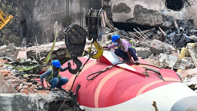 The wreckage of the crashed Air India plane is being lifted by a crane from the roof of the BJ Medical College mess building.