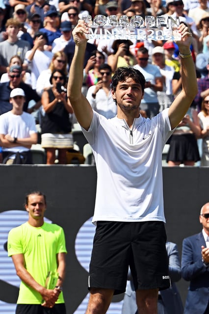 Bühne frei für den Sieger von Stuttgart: Taylor Fritz jubelt mit der Trophäe, während Alexander Zverev im Hintergrund zuschaut