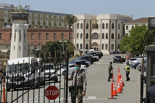 FILE - In this July 9, 2020, file photo, a correctional officer closes the main gate at San Quentin State Prison in San Quentin, Calif. 
