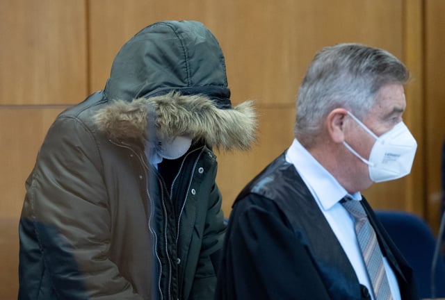 Syrian doctor, 36, known as M. by German media sits with his head covered, accompanied by one of his lawyers Ulrich Endres, as he goes on trial in Frankfurt, Germany, January 19, 2022. Boris Roessler/Pool via REUTERS/File Photo