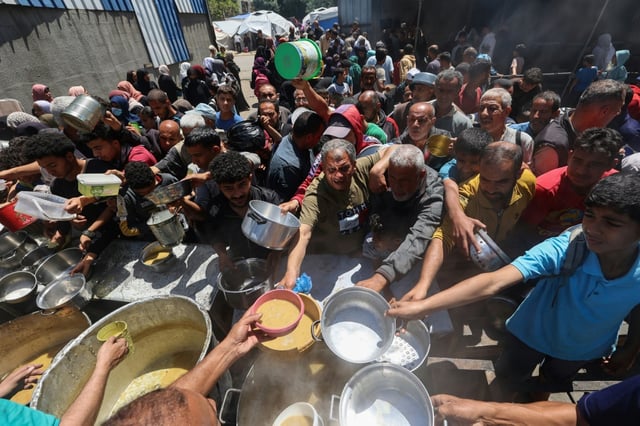 Des Palestiniens font la queue pour un repas chaud dans une cuisine caritative gérée par le Programme alimentaire mondial (PAM) des Nations unies au camp de réfugiés de Nousseirat, dans le centre de la bande de Gaza, le 26 avril 2025