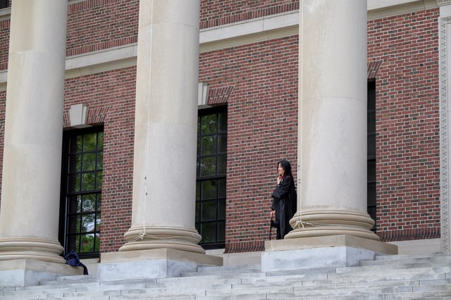 Harvard College graduate, Iris Lang of Florida watches a photo session on the Harvard University campus in Cambridge, Massachusetts, U.S., May 23, 2025.   REUTERS/Faith Ninivaggi