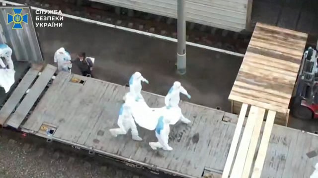 People in hazmat suits carry what is said to be remains of Ukrainian soldiers received from Russia in an unknown location in a screen grab from a Handout video released on June 13, 2025. Security Service Of Ukraine/Handout via REUTERS/ File Photo