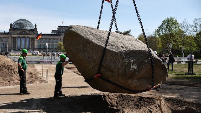 Bauarbeiter legen einen Findling mit Hilfe von Baustellenfahrzeugen an den vorgesehen Gedenkort. Ein tonnenschwerer Findling soll als ein vorläufiges Gedenkzeichen für die polnischen Opfer des Zweiten Weltkriegs und die Opfer der deutschen Besatzungsherrschaft in Polen 1939-1945 errichtet werden.