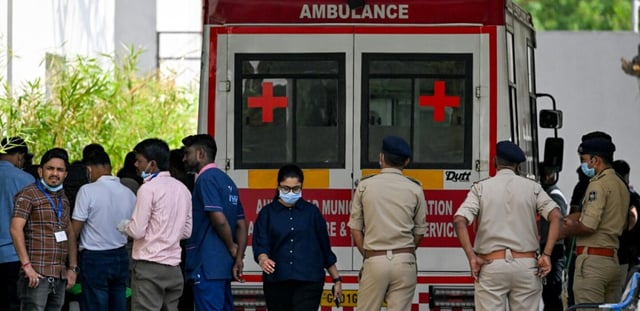 Des policiers et des membres du personnel médical près d'une ambulance stationnée devant une morgue d'hôpital à Ahmedabad, le 15 juin 2025