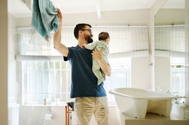 Father holding his baby and taking a towel to dry him after bath time in the bathroom