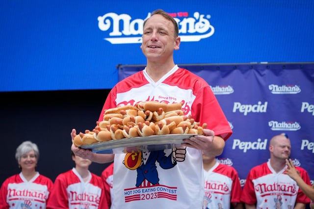 Competitive eater Joey Chestnut holds a plate of hotdogs representing his world record for eating 76 hotdogs and buns in ten minutes during a weigh-in ceremony before the Nathan&#39;s Famous July Fourth hot dog eating contest, Monday, July 3, 2023, in New York. (AP Photo/John Minchillo)