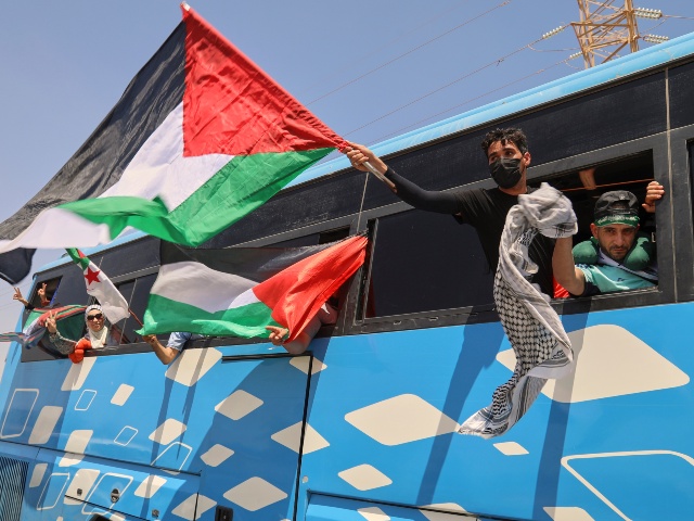 Members of a humanitarian convoy of at least 1,500 people, including activists and supporters from Algeria and Tunisia, wave Palestinian flags from a bus as the group travels toward Gaza via Egypt's Rafah Crossing, in Zawiya, Libya, Tuesday, June 10, 2025. (AP Photo/Yousef Murad)