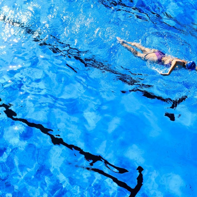 Eine Frau schwimmt in einem Freibad.