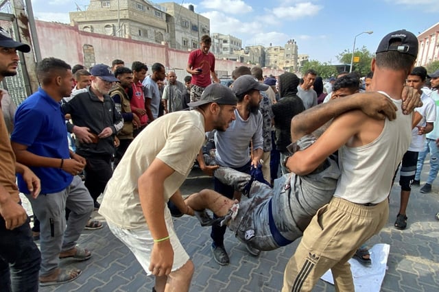 Des Palestiniens transportent un homme blessé près un centre d'aide de Kahn Youès dans le territoire de Gaza; me 17 juin 2025.