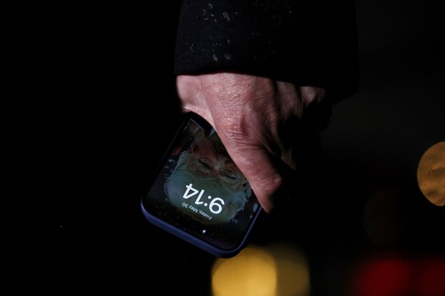 U.S. President Donald Trump holds a mobile phone with his image on it, after his return from Pennsylvania, at Joint Base Andrews, Maryland, U.S., May 30, 2025. REUTERS/Leah Millis REFILE - CORRECTING LOCATION FROM "WASHINGTON, D.C." TO "JOINT BASE ANDREWS, MARYLAND".