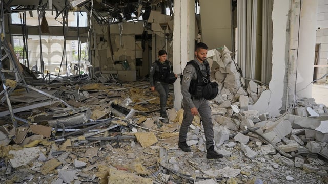 Israeli border police officers walk at the entrance of a residential building hit by a missile launched from Iran, in Petah Tikva, Israel, Monday, June 16, 2025. (AP Photo/Baz Ratner)