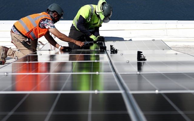 FILE: Workers install solar panels at the Port of Los Angeles on April 21, 2023.