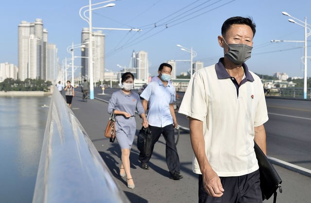 People wearing face masks for protection against Covid-19 walk in Pyongyang on Aug. 19, 2021.