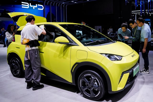 People use their phones in front of the BYD Seagull that is displayed at the Auto Shanghai show, in Shanghai, China April 19, 2023. REUTERS/Aly Song/File Photo