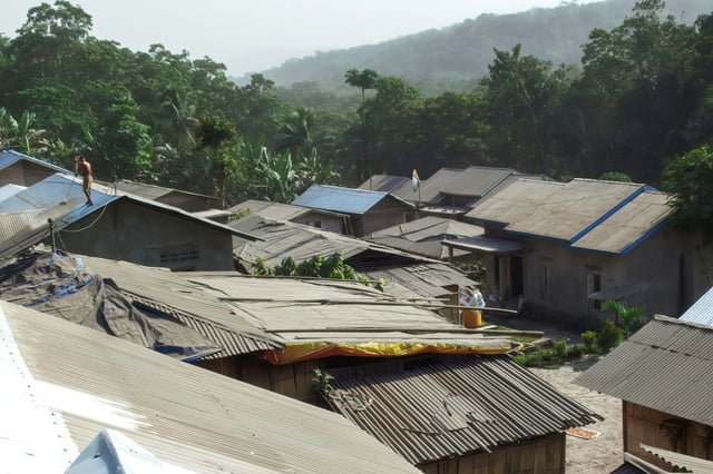 Des villageois nettoient les toits de leurs maisons des cendres volcaniques au lendemain de l'éruption du mont Lewotobi Laki-Laki à Sikka, dans l'est de Nusa Tenggara, le 18 juin 2025 en Indonésie