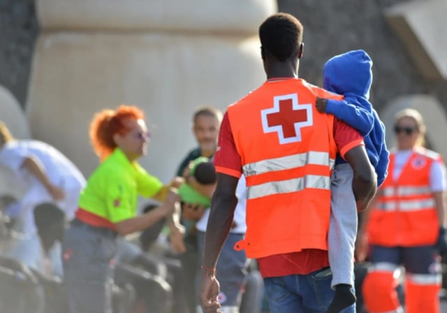 Un voluntario de Cruz Roja en El Hierro atiende a un niño llegado en cayuco al puerto de La Restinga, en una foto de octubre de 2023