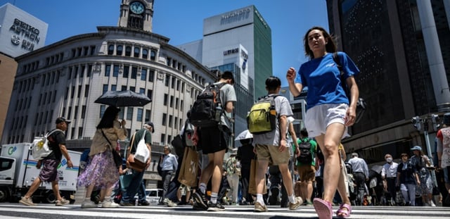 Des piétons dans une rue du quartier de Ginza à Tokyo où les températures ont dépassé les 34°C, le 18 juin 2025