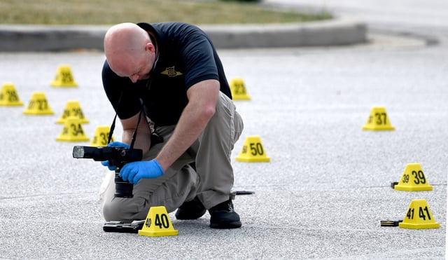 A investigator with the Indiana State Police photographs a gun next to an evidence marker on Gateway Boulevard near Ind. 49 and the Indiana Toll Road exit following a shooting in Chesterton, Indiana, Wednesday, June 18, 2025. (Andy Lavalley/for the Post-Tribune)