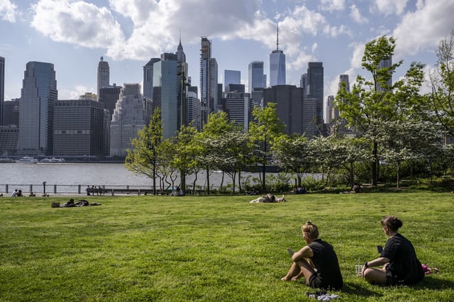People sit in Brooklyn Bridge park on a warm day on May 8, 2024 in New York. 