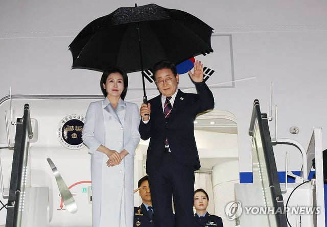 This photo, taken on June 17, 2025, shows President Lee Jae Myung (R) waving next to first lady Kim Hea Kyung on a presidential plane at an airport in Calgary, Canada. (Yonhap)  