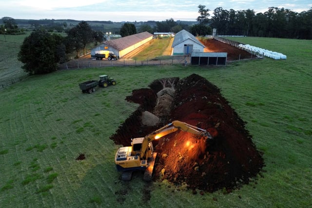 An excavator moves earth next to a hole in the ground at a poultry farm after Brazil confirmed its first outbreak of bird flu on Friday, triggering protocols for a country-wide trade ban from top buyer China and state-wide restrictions for other major consumers, in Montenegro, Brazil May 16, 2025. REUTERS/Diego Vara/File Photo