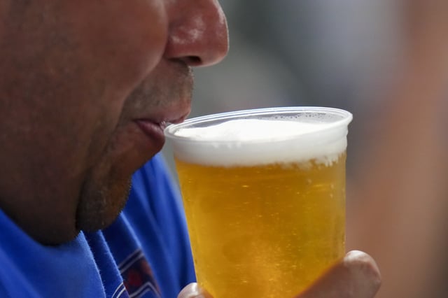 A spectator drinks beer during the sixth inning of a baseball game between the Texas Rangers and the Toronto Blue Jays Tuesday, May 27, 2025, in Arlington, Texas. 