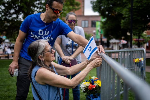 Lisa Turnquist of Louisville, Colorado, lays flowers and a flag at the site of the attack outside the Boulder County Courthouse on June 2, 2025.