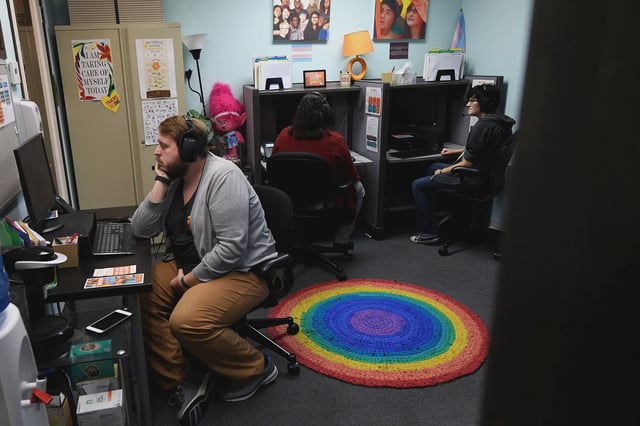 Crisis Service Coordinator Chris Bright (left) looks at a computer monitor with volunteers at the Trevor Project Call Center in West Hollywood, California in January 2017.