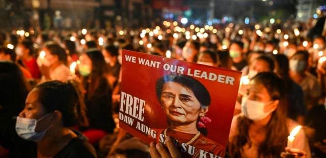 Un manifestant tient une affiche avec une image de l'ex-dirigeante détenue Aung San Suu Kyi lors d'une veillée aux chandelles à Rangoun, le 13 mars 2021