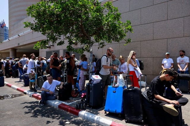 People arrive with their luggage before the departure of buses slated to evacuate foreign passport holders, mainly European and Polish, out of Israel, at a meeting point in Tel Aviv