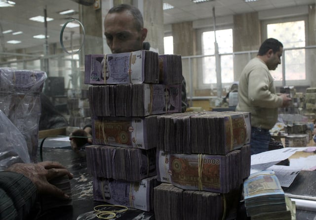 Bundles of Syrian currency notes are stacked up as an employee counts money at Syrian central bank in Damascus, Syria, January 12, 2025. REUTERS/Firas Makdesi/File Photo