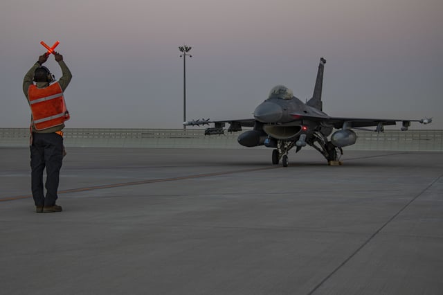 In this handout photo from the U.S. Air Force, an airman guides an F-16 Fighting Falcon during training at Al-Udeid Air Base, Qatar, Jan. 24, 2022.