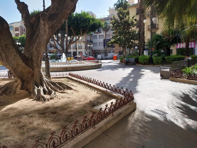 Una mujer se protege del sol con un paraguas en la plaza Mayor de Alzira.