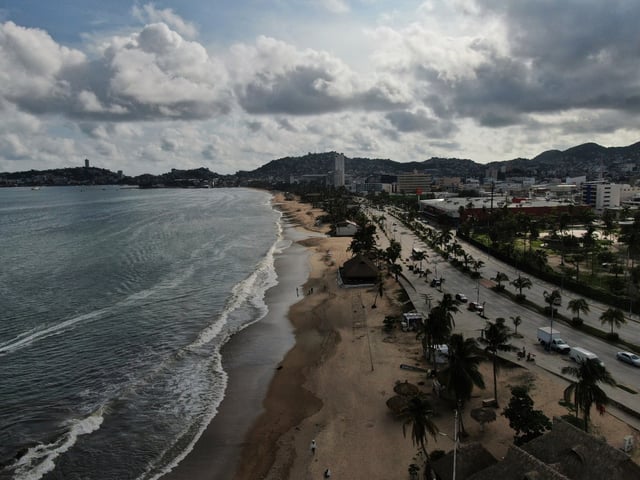 Tourists stroll along the beach shore before the arrival of Hurricane Erick, in Acapulco, Mexico, Wednesday, June 18, 2025. (AP Photo/Fernando Llano)