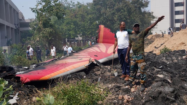 Menschen stehen in der Nähe der Trümmer eines abgestürzten Flugzeugs in Ahmedabad.