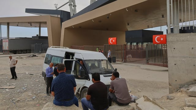 People wait after crossing from Iran into Turkey at Gurbulak Bazargan border post in Gurbulak, Turkey, on Monday.