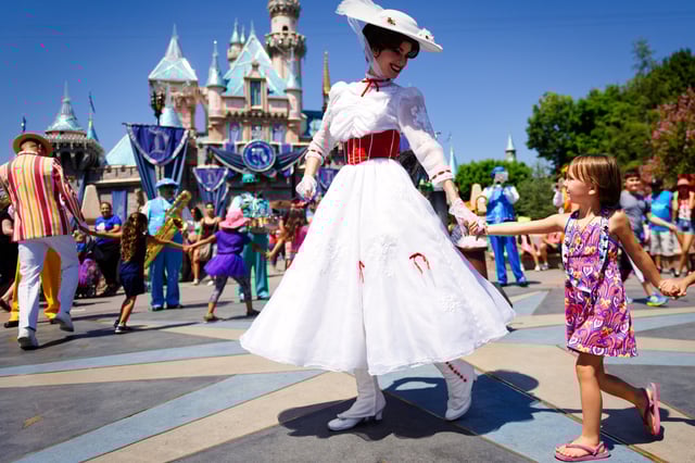 A woman dressed as Mary Poppins smiles at a young child as she leads a line of children in front of Cinderella&#39;s castle at Disneyland in California during Disney&#39;s 60th Diamond Celebration, August 10, 2016.