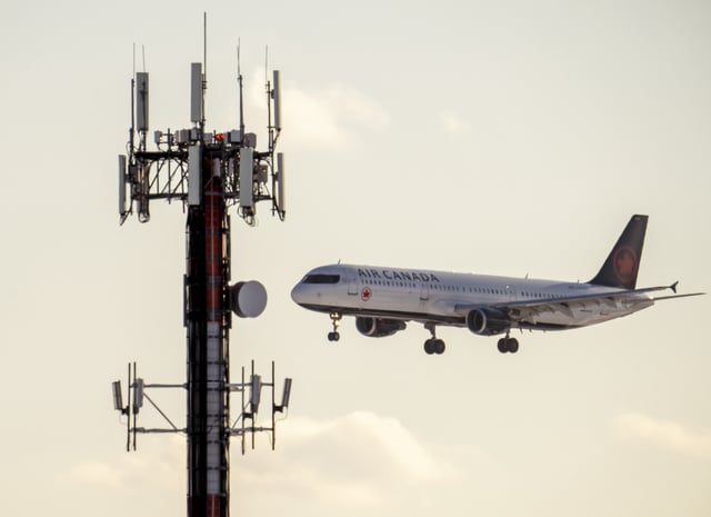 An Air Canada jet flies past a cell phone tower as it comes in to land at Pearson Airport in Toronto on Thursday January 20, 2022. 