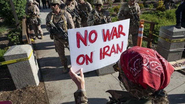 A protester holds a sign in front of U.S. Marines in downtown Los Angeles on June 19. Photo: Jon Putman/Anadolu via Getty Images