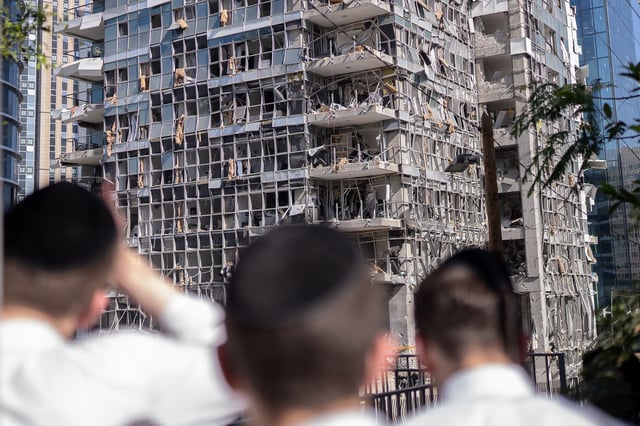 People stand in front of a building damaged by an Iranian missile attack in Ramat Gan, Israel, on Thursday, June 19.